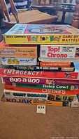 Stack of vintage board games including Merv Griffin's Word for Word, Moocho Sudoku, Emergency!, Bug-A-Boo, Careers, Kojak and others showing side spines
