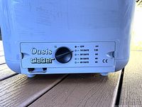 Close-up of the control dial on the Oasis Claber irrigation system showing settings for off, 10, 20, 30, and 40 days watering durations with corresponding water volumes in milliliters.