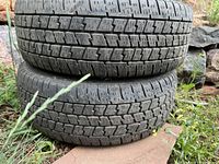 Two used tires stacked on top of each other showing tread pattern and condition.
