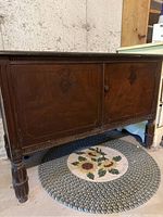 Frontal view of antique wooden cabinet showing carved detailing and two wooden doors.