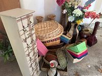 Photo showing a collection of woven baskets, vases with faux flowers, and a tall decorated storage box