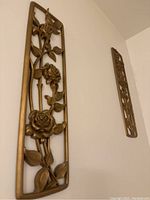 Side angle of second gilded carved floral wall plaque with blossoms and leaves.