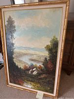 Frontal view of the vintage oil painting showing the full landscape scene and the gold-tone bamboo-style frame.