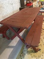 Side angle showing the rustic barn red picnic table with one bench underneath, angled X-style legs support enhanced structure.