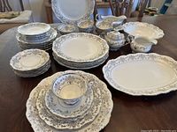View of the full set: stacked plates, cups, saucers, serving platter, and bowls detailed with platinum trim and floral Romance pattern