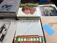 Stack of various vintage vinyl record albums including Mary Poppins soundtrack, Sesame Street Book & Records, Fleetwood Mac, Mister Rogers' Neighborhood, and Carpenters albums.