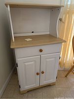 Front view of the microwave cart showing the natural wood top, white body, and wooden knobs.