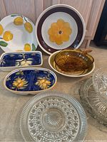 Overview of all bowls including Italian pottery pieces with lemon and floral painted designs, yellow flower bowl, amber glass leaf bowls, and clear glass pressed bowls.