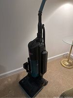 Full side view of Fantom Fury upright vacuum cleaner showing black and blue design with attached hose.