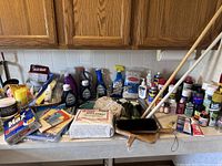 Photo showing a broad view of all cleaning products, tools, sprays, and pest control items on the kitchen counter.