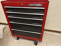 Front view of red and black chest showing all five drawers and lower casters