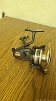 Side angle showing the entire Daiwa J-16 spinning reel on wooden surface.