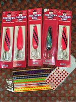 Nine Northern King fishing spoons in original packaging and assorted fishing lure stickers.