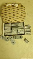 Box with 19 assorted Saeco lead alloy ingots, showing both rectangular and slot-shaped bars.