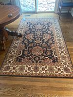 Full view of the 5x8 feet Asian inspired area rug in situ on hardwood flooring under a round wooden table.