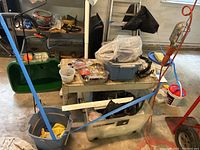 View of Scott spreader, ladder, bucket with gloves, bins with miscellaneous hardware and tools in garage setting.