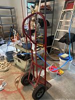 Full view of red Milwaukee hand truck with black wheels and garage background.