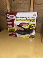 Box of Precision NuWave 2 Revolutionary Portable Induction Cooktop showing product features and bonus ceramic fry pan.