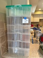 Front view of the six-tier plastic ornament storage container with a green lid, shown on kitchen countertop.
