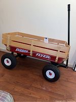Full side view of the Radio Flyer wagon showing red metal body, wooden side rails, black tires with white rims, and pull handle.