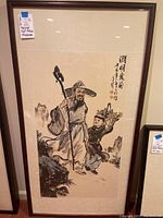 Close-up of framed print showing elderly man with walking stick and child with flowers, traditional Chinese brush style