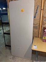 Gray folding table leaning against the wall showing full top surface and collapsible design