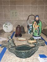 Photo showing entire lot of Asian inspired ceramic decor items arranged on countertop with tiled backsplash.