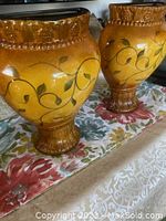 Pair of ceramic wall hanging vases on floral tablecloth showing front and side details with amber glaze and raised bead rim.