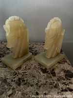 View showing the pair of carved marble horse head bookends on a marble surface.