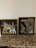 Two framed Tibetan vintage pictures on a marble surface, showing full artwork and gold-finished frames.