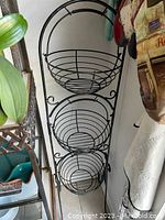 Front view of the black metal 3 tier fruit and vegetable basket storage shelf showing three wire baskets in vertical arrangement.