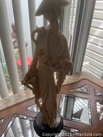 Full view of the marble resin sculpture of bearded Asian man with exotic birds standing on a base.