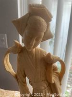 Close-up of the upper portion of the marble resin sculpture showing the woman's detailed face, headwear, and two exotic birds on her arm and shoulder.