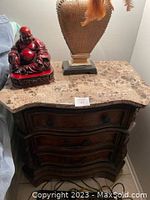 Dark wood night stand with a granite top, decorative lamp and Buddha figurine on top