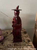 Front view of handcarved rosewood Japanese fisherman statue with fishing rod and traditional hat.