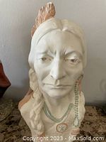 Front view of the Native American head bust showing facial features, braided hair, beaded necklaces and color on feathers.