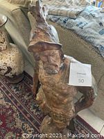 Stone carved Roman gladiator statue standing 44 inches tall, detailed close up on the helmet and face with a label attached to the arm.