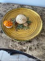 Angled view of the mushroom hors d'oeuvre plate showing ceramic mushrooms and leaf motif on a textured plate base colored in shades of yellow and brown.