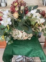 Full view of the footed vase with the artificial flower arrangement on top, showing height and color.