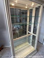 Close-up photo of the interior showing multiple adjustable glass shelves and mirrored back panel inside the cabinet.