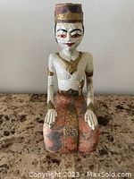 Front view of hand-painted carved wood Egyptian-style statue with fabric skirt, showing facial detail and crackle paint finish.