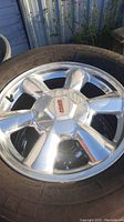 Close-up photo of one aluminum rim with GMC center cap and mounted tire showing details and condition.