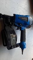 Blue Mastercraft coil roofing nailer tool with black coil magazine attached, side view showing tool branding and grip.