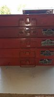 Stacked set of 5 orange metal parts bins with latches and labels