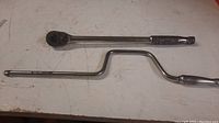 Both Snap On tools laid flat on a workbench showing the full length and shape of each tool.