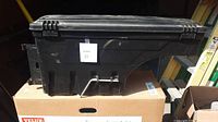 Side view of the black plastic tip out tool box showing molded shapes and mounting hardware attachment points.