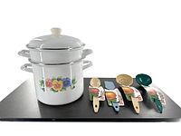 Photo of 3-piece white enamel double boiler stock pot set with floral decoration and 5 colorful cooking utensils laid out beside it