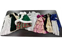 Seven vintage Barbie and friends princess dresses laid out, showing variety of colors and fabrics including white lace, green velvet, pink plaid, and gold brocade.