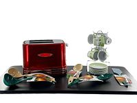 Red 2-slice Retro Series Nostalgia toaster with minor wear marks on glossy finish, alongside green and beige Hutzler cooking utensils, and Tannex espresso cup set with stand.