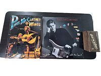 Paul McCartney & Wings coffee table book, Paul McCartney vinyl album, and Discwasher kit shown on black surface